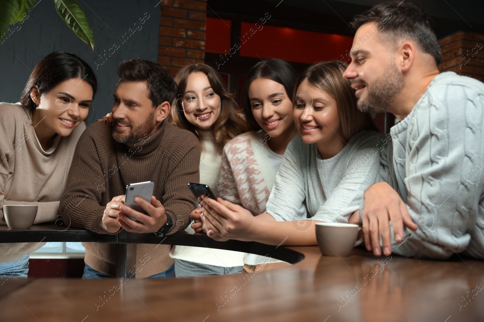 Photo of Friends with drinks and smartphones spending time together in cafe