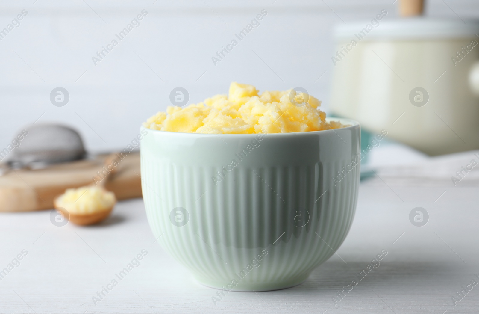 Photo of Bowl of Ghee butter on white wooden table, closeup