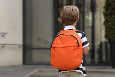 Photo of Little boy walking to kindergarten outdoors, back view. Space for text