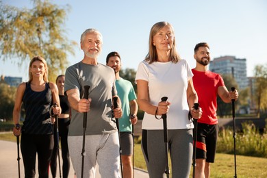 Photo of Group of happy people practicing Nordic walking with poles in park