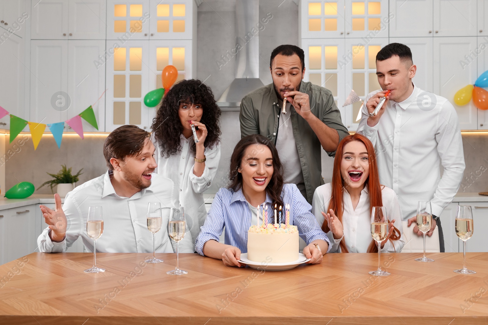 Photo of Happy friends with tasty cake celebrating birthday in kitchen