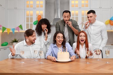 Photo of Happy friends with tasty cake celebrating birthday in kitchen