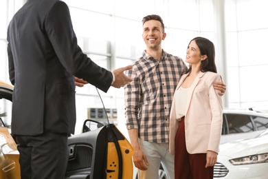 Photo of Young couple buying new car in salon