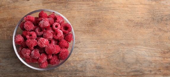 Tasty frozen raspberries on wooden table, top view. Space for text