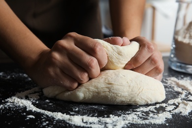 Photo of Woman kneading dough for pastry on table