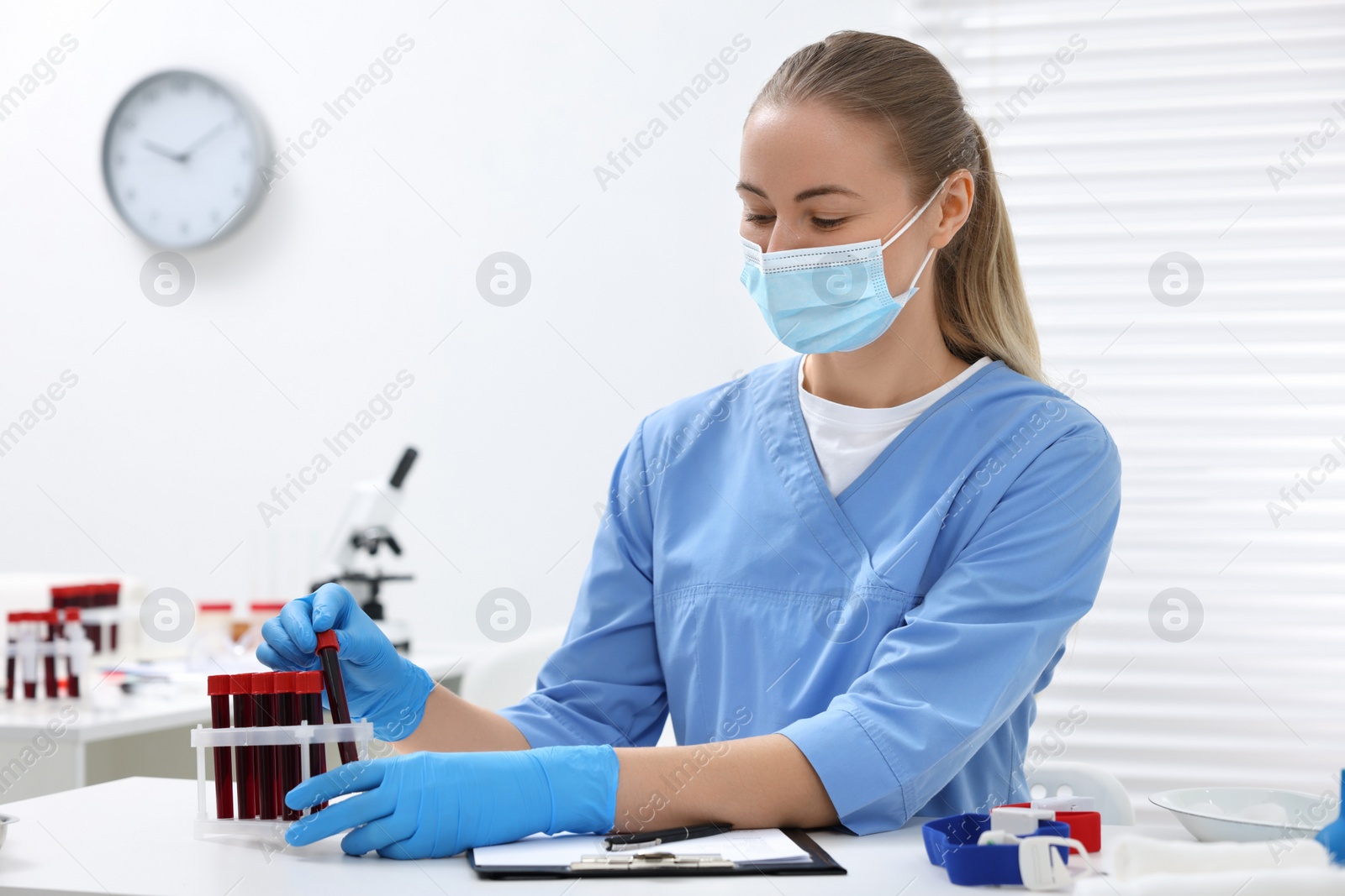 Photo of Laboratory testing. Doctor with blood samples in tubes at white table indoors