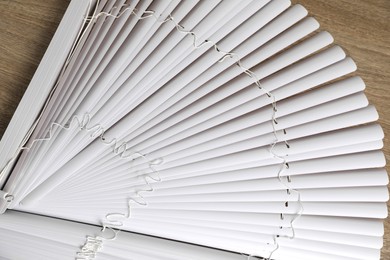 Photo of Stylish horizontal window blinds on wooden table, top view