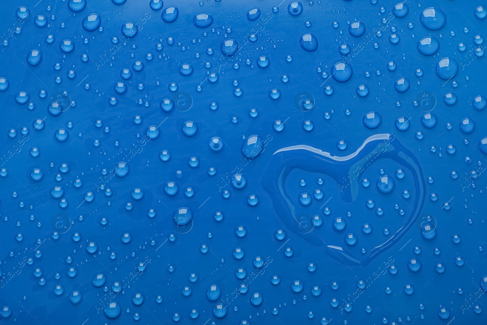 Photo of Heart shape of water and drops on blue background, top view