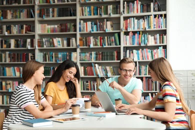 Photo of Young people discussing group project at table in library