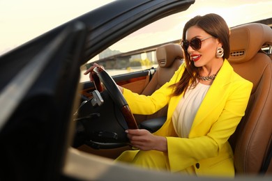 Beautiful businesswoman in luxury convertible car outdoors