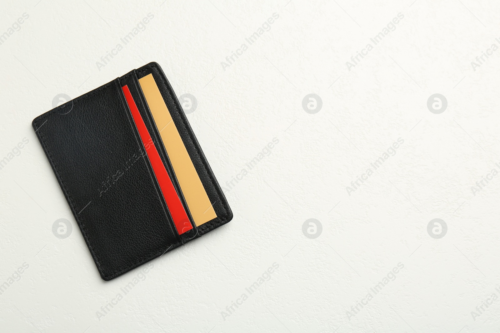 Photo of Leather business card holder with colorful cards on white table, top view. Space for text