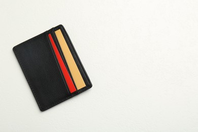 Photo of Leather business card holder with colorful cards on white table, top view. Space for text