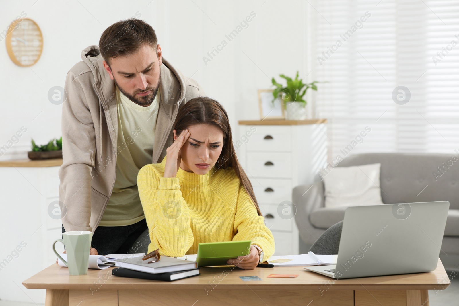 Photo of Young couple discussing family budget at table in living room