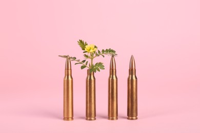 Photo of Bullets and beautiful flower on pink background
