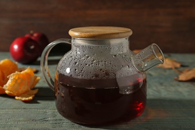 Photo of Glass teapot with hot beverage on light blue wooden table