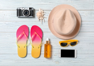 Flat lay composition with beach objects and mobile phone on wooden background