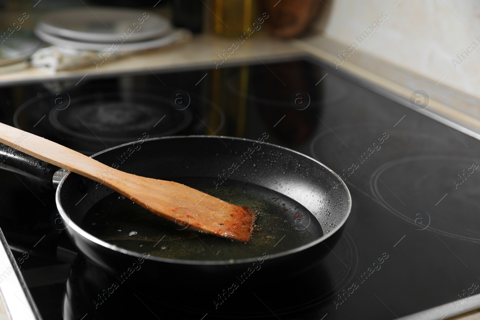 Photo of Frying pan with spatula and used cooking oil on stove