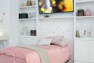 Photo of Stylish teenager's room interior with comfortable bed, workplace and modern TV set