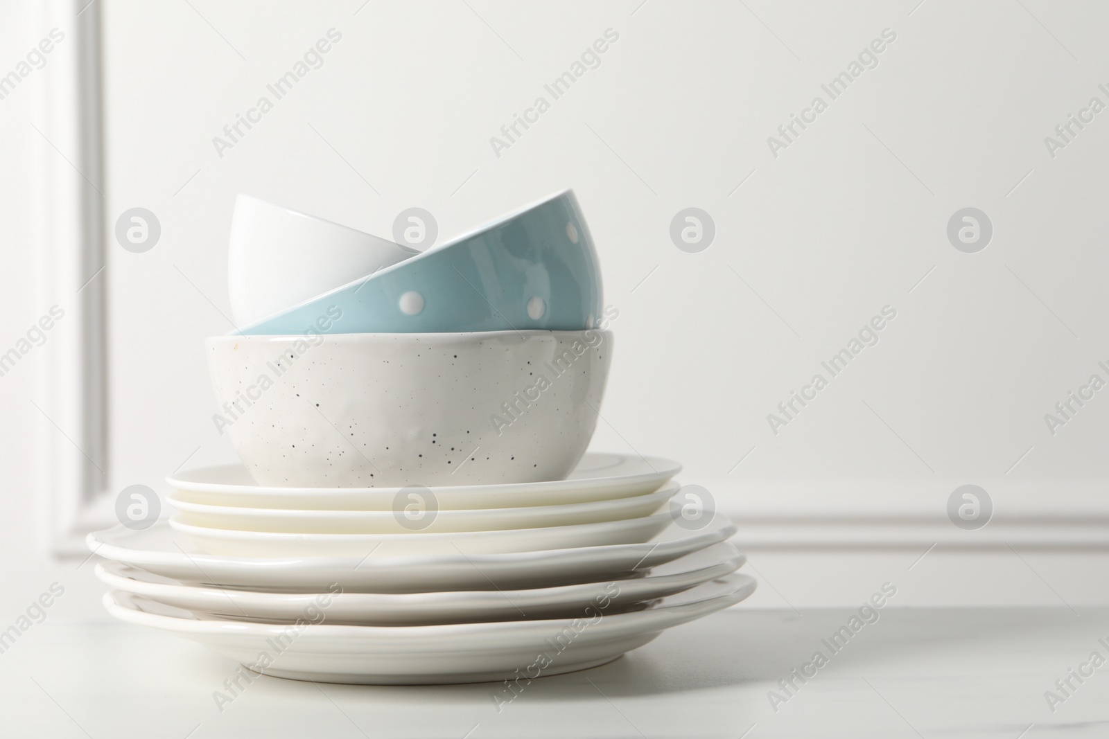 Photo of Stack of beautiful ceramic dishware on white table, space for text