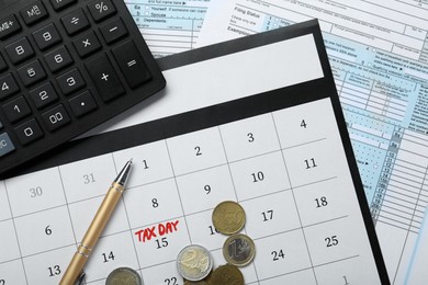 Photo of Calendar with date reminder about tax day, documents, coins, pen and calculator, top view