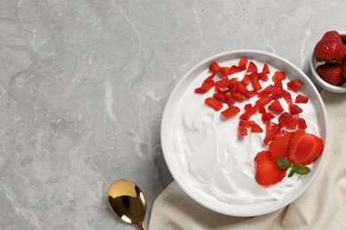 Photo of Delicious yogurt with strawberries served on grey marble table, flat lay. Space for text