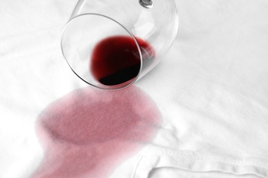 Overturned glass and spilled exquisite red wine on white t-shirt