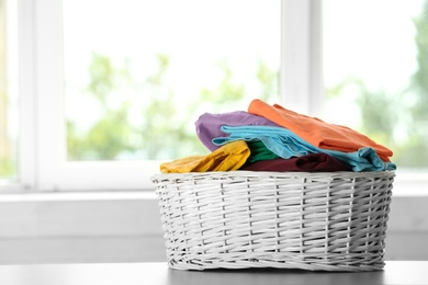 Photo of Basket with clean laundry on table at home, space for text