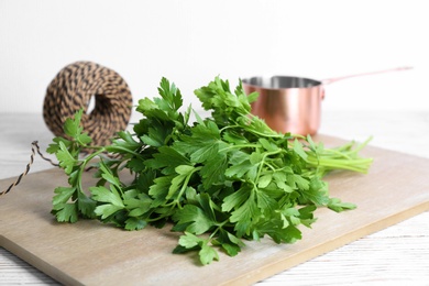 Photo of Wooden board with fresh green parsley on table