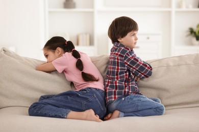 Upset brother and sister on sofa at home