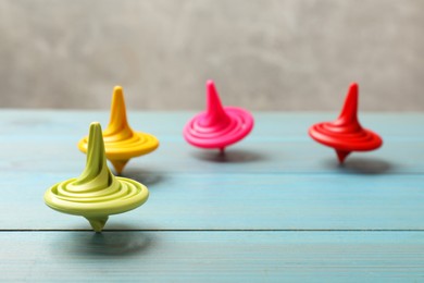 Photo of Bright spinning tops on light blue wooden table, closeup