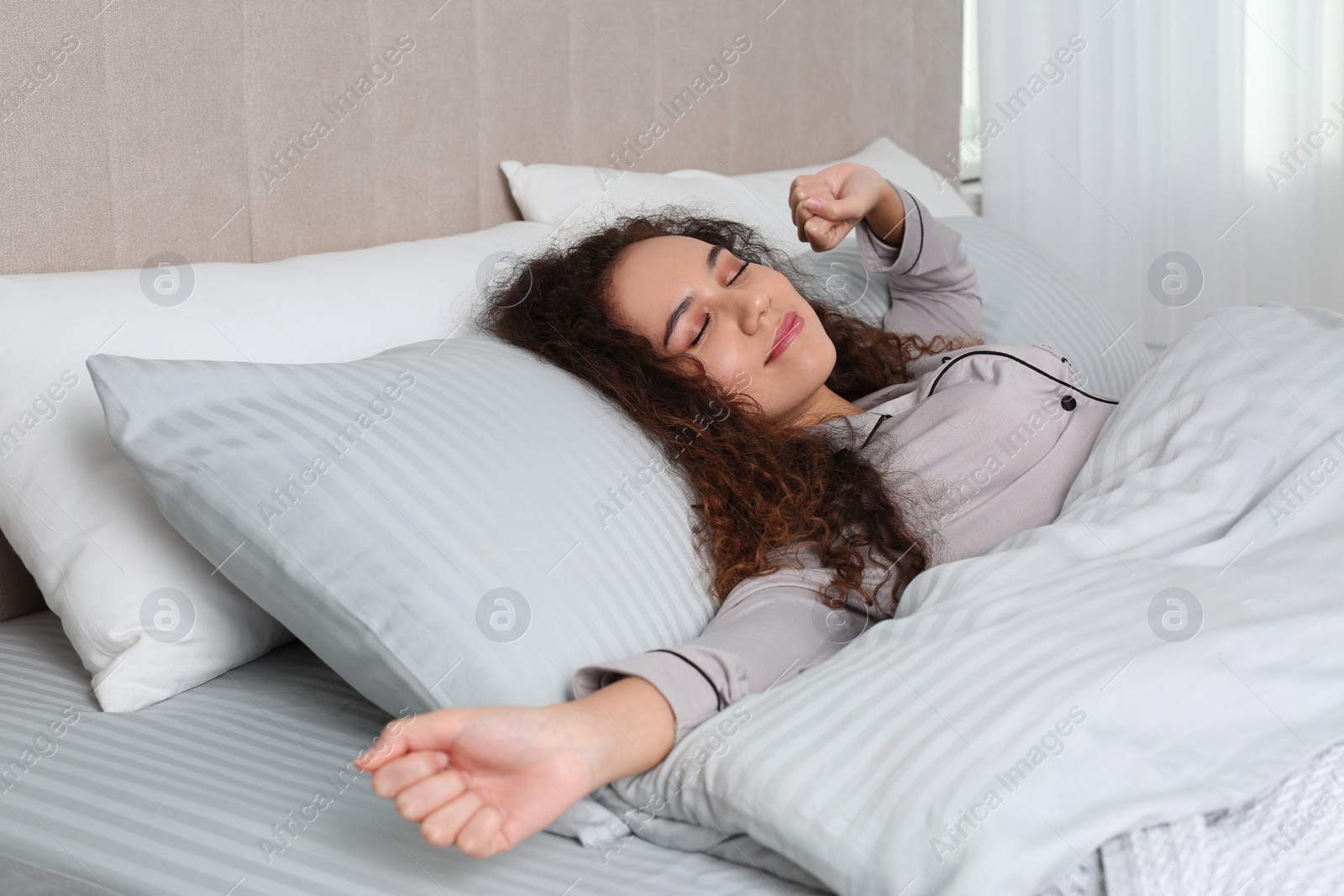 Photo of Beautiful African American woman stretching in bed at home