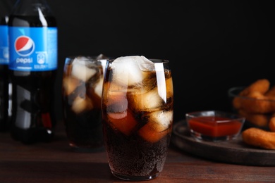 Photo of MYKOLAIV, UKRAINE - FEBRUARY 15, 2021: Glass of Pepsi with ice on wooden table