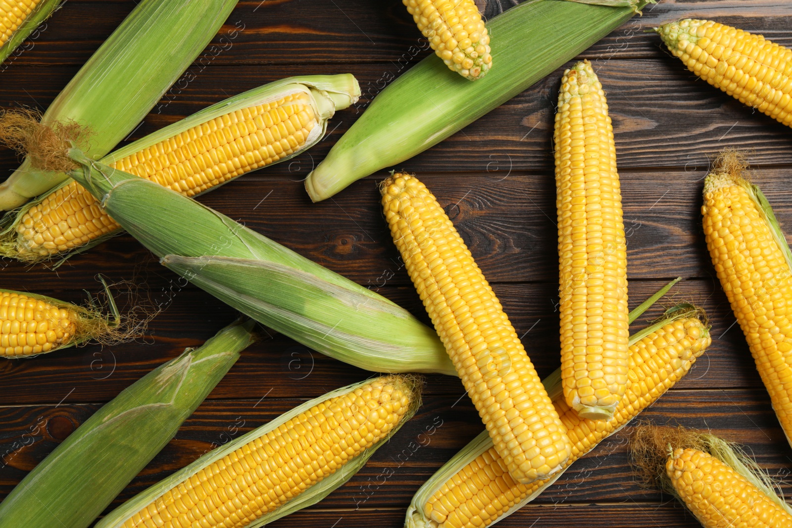 Photo of Tasty sweet corn cobs on wooden table, flat lay