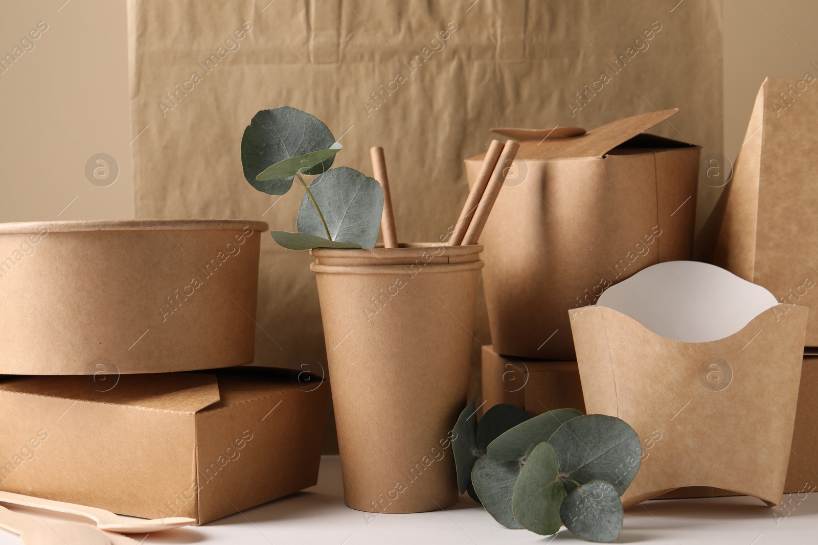 Photo of Eco friendly food packaging. Paper containers, bag and eucalyptus branches on white table