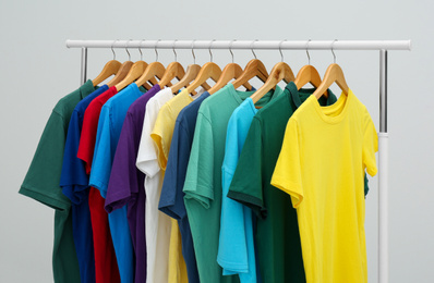 Photo of Rack with colorful t-shirts on light background