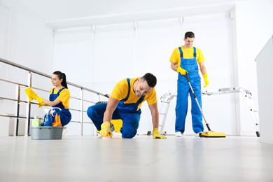 Photo of Team of professional janitors cleaning room after renovation