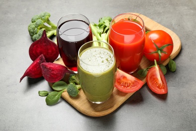 Photo of Delicious vegetable juices and fresh ingredients on grey table