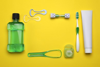 Photo of Flat lay composition with tongue cleaners and teeth care products on yellow background. Space for text