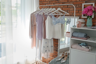 Photo of Stylish dressing room interior with clothes on rack