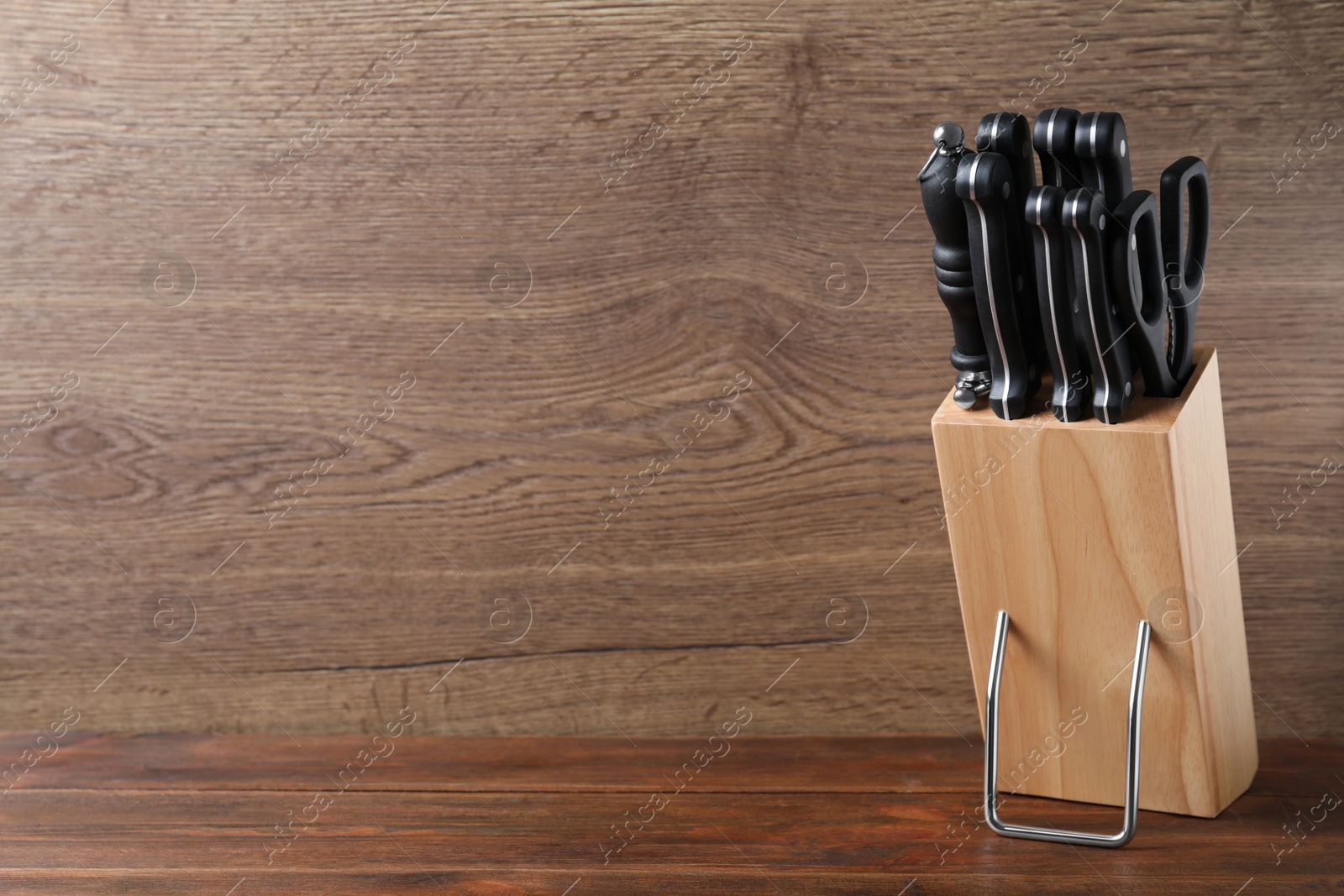 Photo of Holder with set of knives on wooden table. Space for text