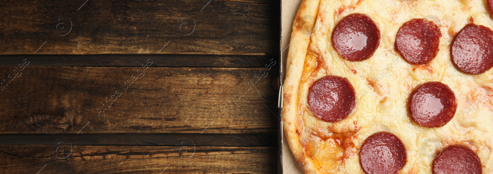 Image of Top view of hot delicious pizza on wooden table, space for text. Banner design 