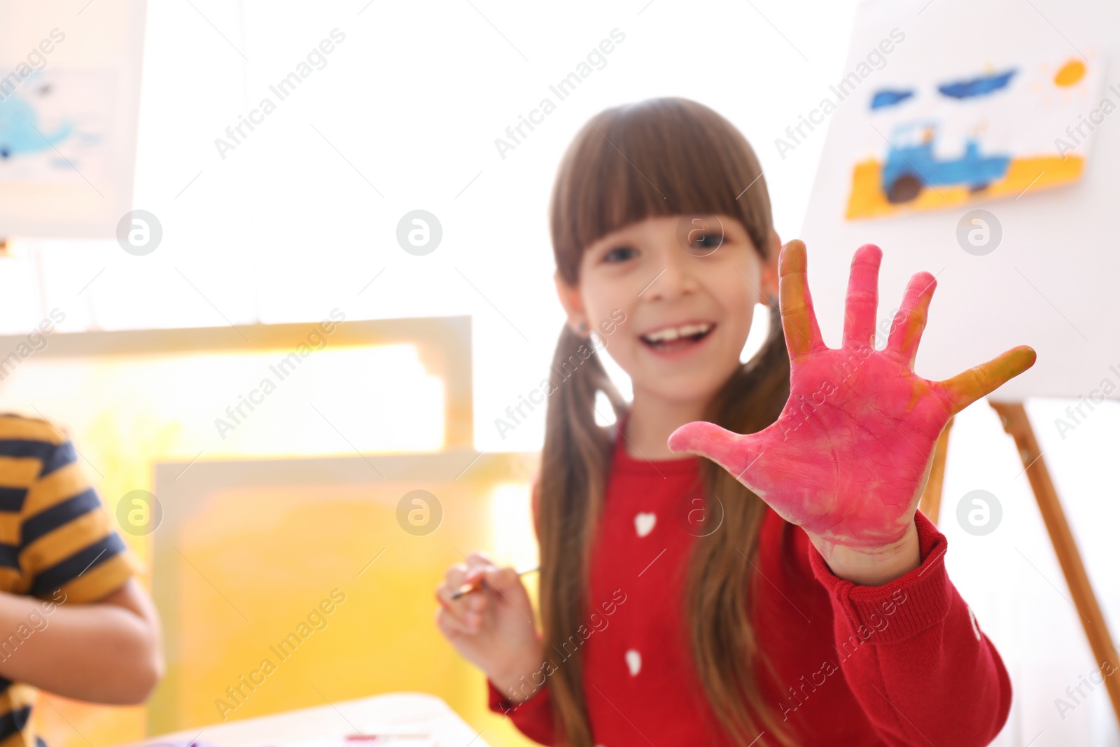 Photo of Cute little child with painted palm in room