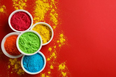 Photo of Colorful powders in bowls on red background, flat lay with space for text. Holi festival celebration
