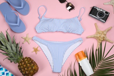 Flat lay composition with swimsuit and beach accessories on pink background