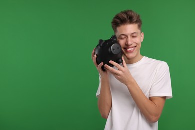 Photo of Happy man with piggy bank on green background. Space for text