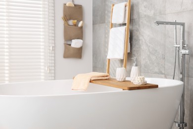 Photo of Set of different bath accessories and soap on tub in bathroom, space for text