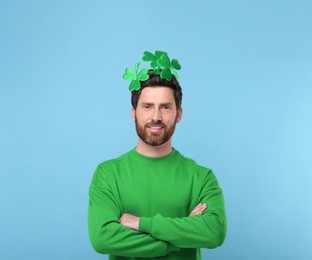 Image of St. Patrick's day party. Man with green clover headband on light blue background