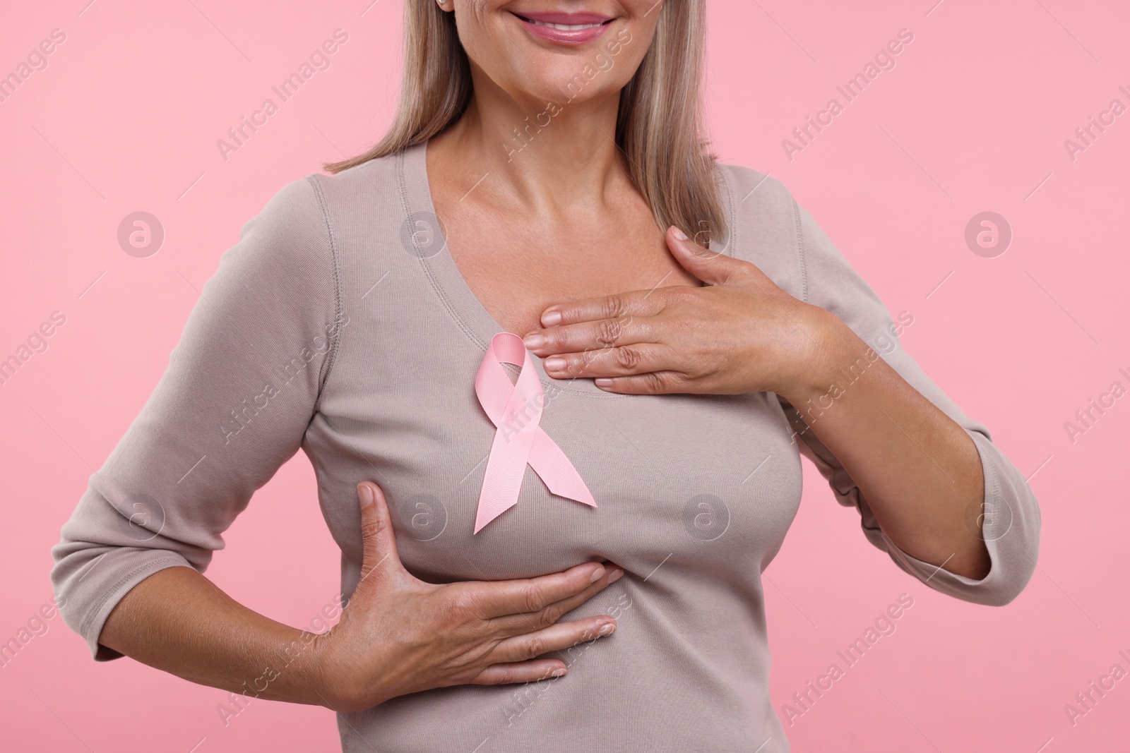 Photo of Woman with pink ribbon on color background, closeup. Breast cancer awareness