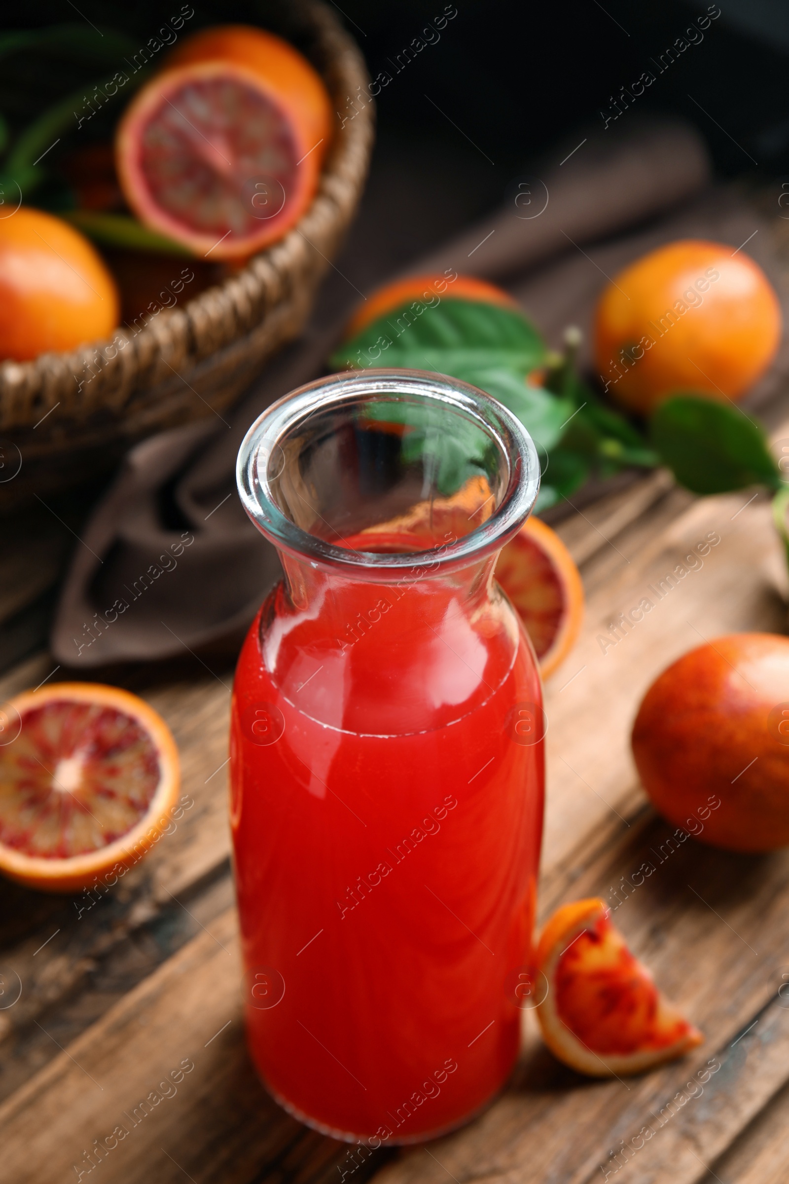 Photo of Tasty sicilian orange juice in glass bottle and fruits on wooden table