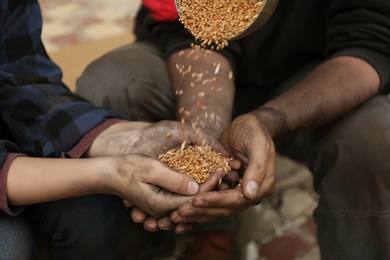 Photo of Poor homeless people taking wheat from donator outdoors, closeup